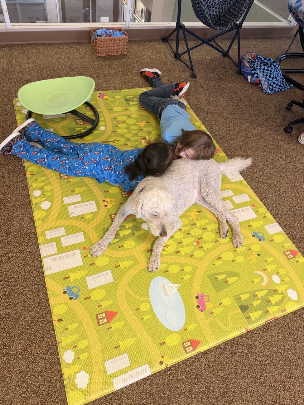 Children resting on a play mat beside a gentle dog