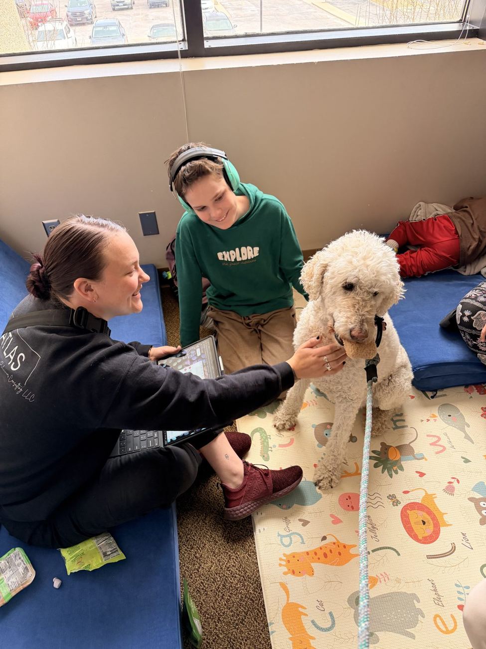 A therapist and child sharing a quiet moment with a therapy dog at Atlas